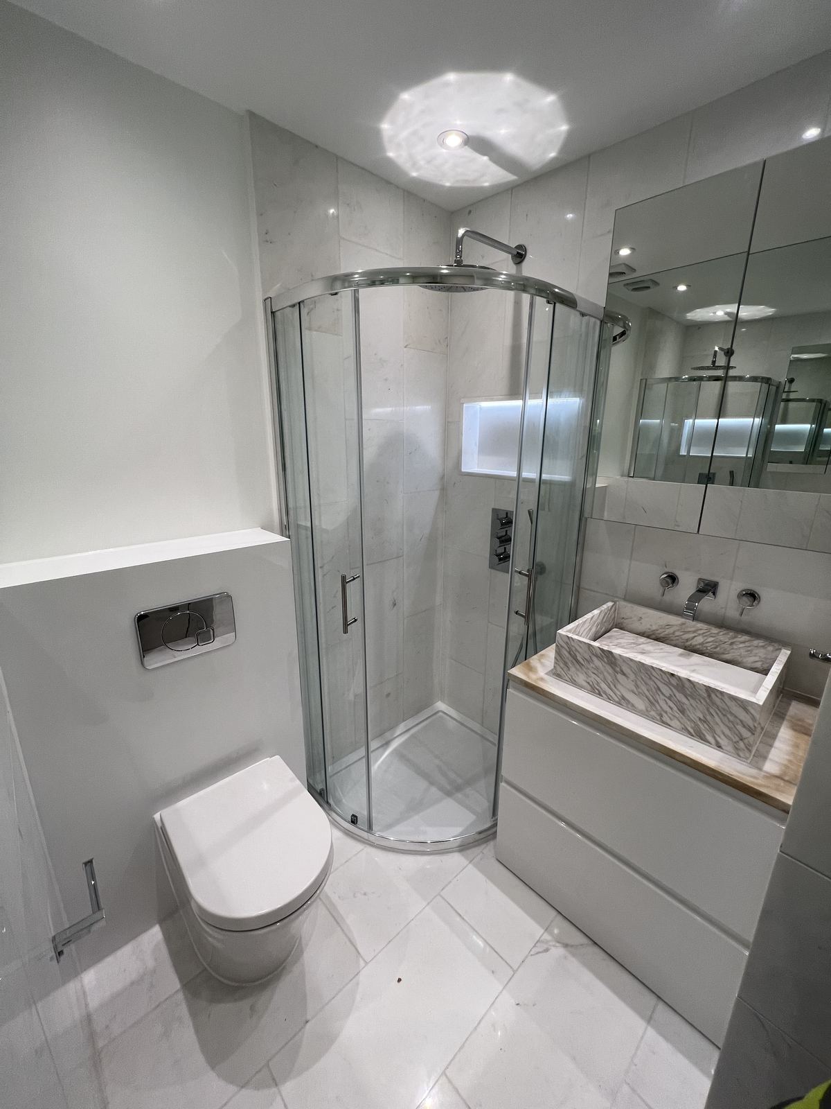Compact white marble en-suite with a curved shower