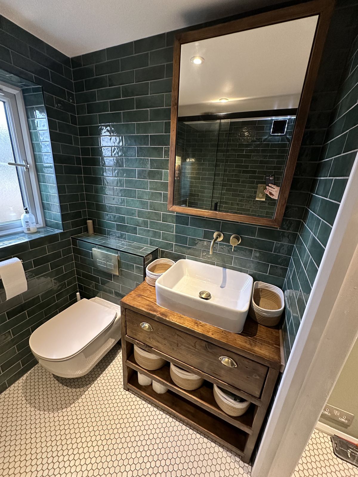 Deep green tiled shower room with a walnut vanity and brass