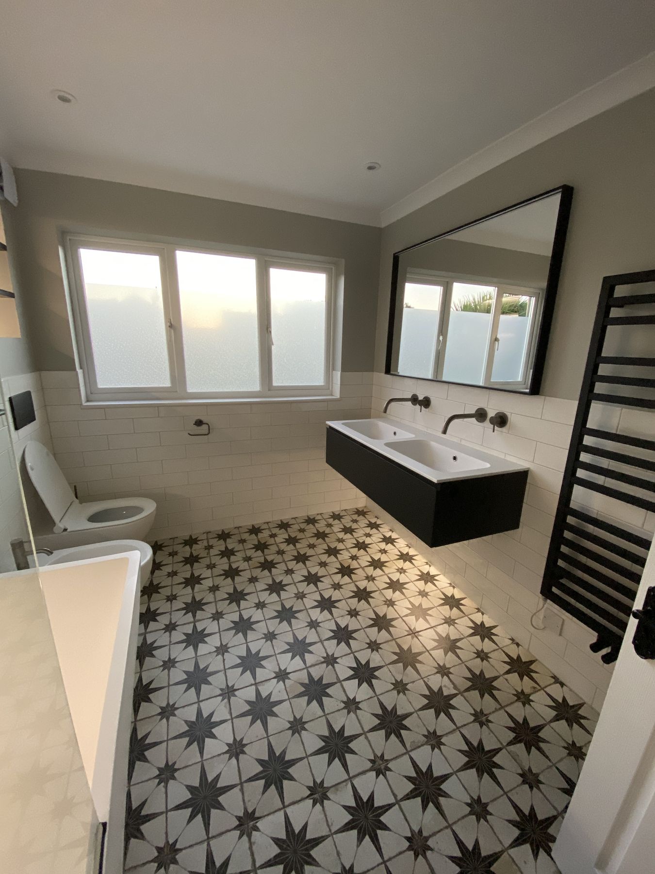 Family bathroom with star-pattern floor tiles, white metro tiles and a black double vanity