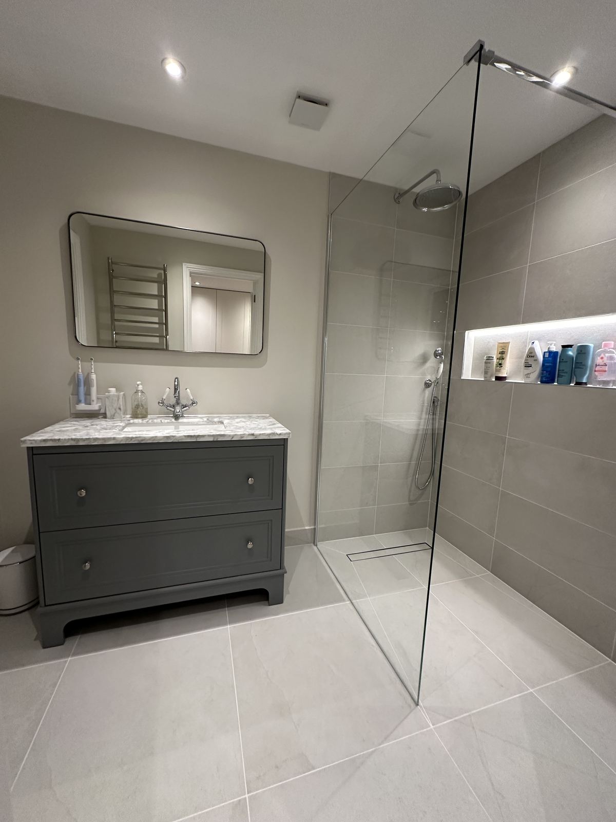 Walk-in shower with a long lit niche and a grey shaker vanity