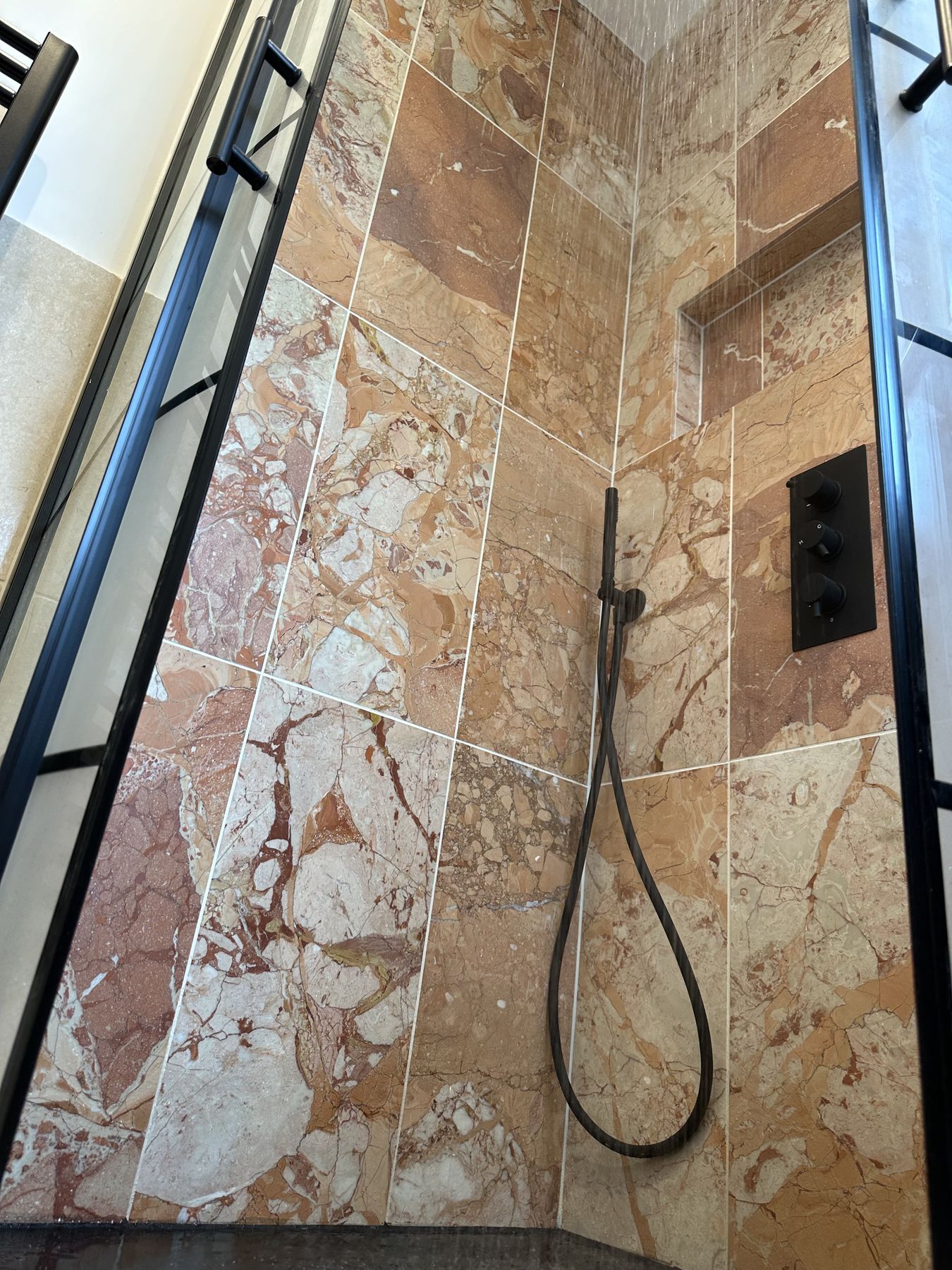 Rose marble shower wall with black fittings